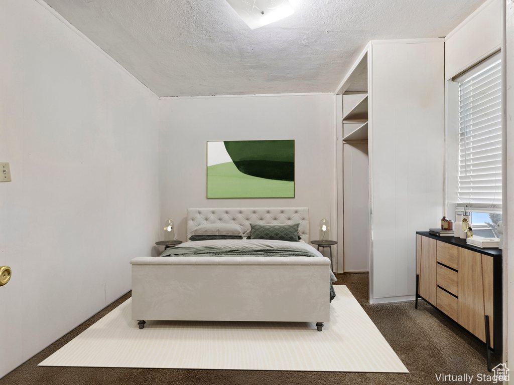 Bedroom with dark carpet, a textured ceiling, and multiple windows