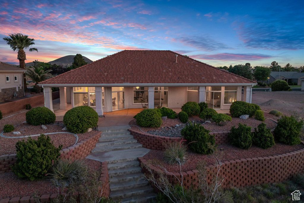 Mediterranean / spanish home with a tiled roof, stucco siding, and a patio area