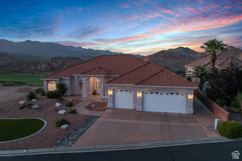 Mediterranean / spanish house featuring a mountain view, a garage, a tile roof, and driveway