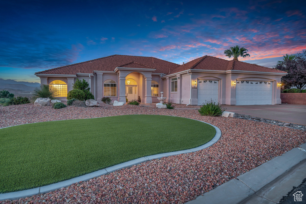 Mediterranean / spanish-style house with an attached garage, a tiled roof, concrete driveway, and stucco siding
