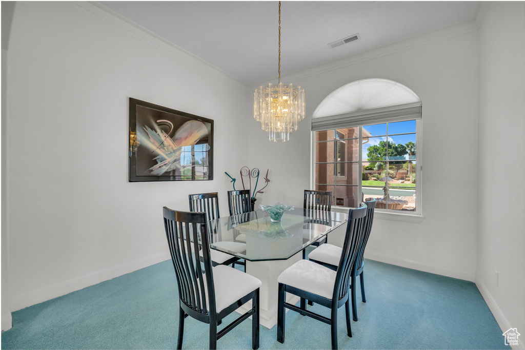 Dining room with ornamental molding, carpet floors, and a chandelier