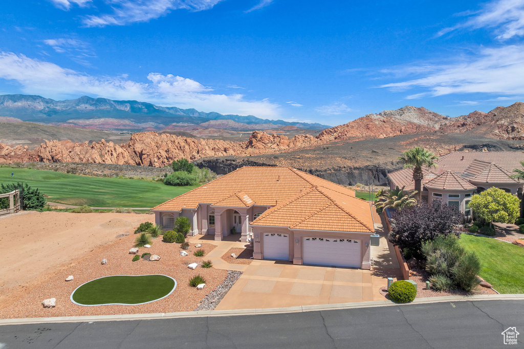 Mediterranean / spanish home with an attached garage, a mountain view, a tile roof, driveway, and stucco siding