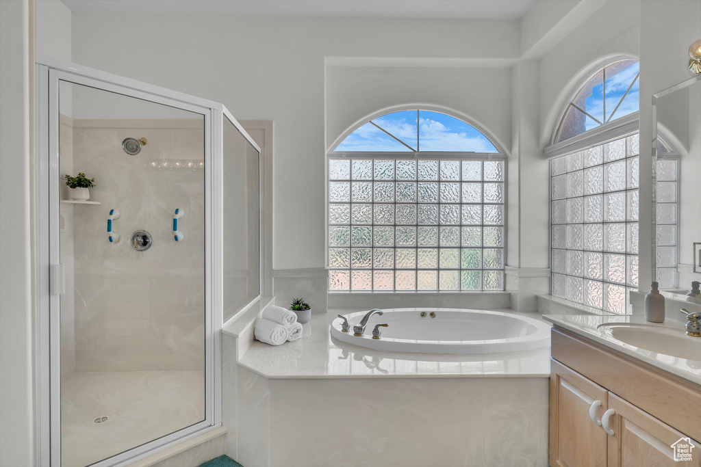 Full bathroom with healthy amount of natural light, a stall shower, vanity, and a bath