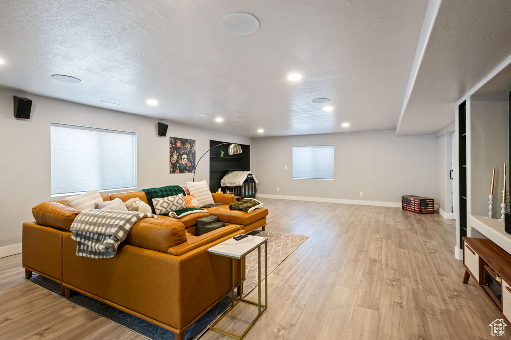 Living area with light wood finished floors, a textured ceiling, and recessed lighting