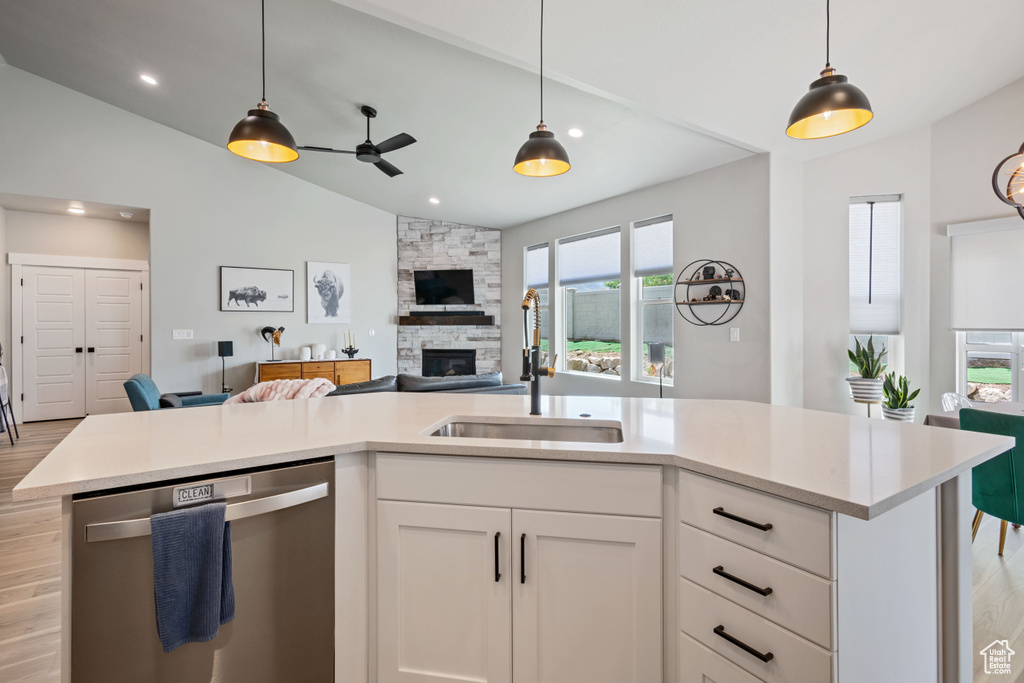 Kitchen with stainless steel dishwasher, vaulted ceiling, open floor plan, a ceiling fan, and light countertops