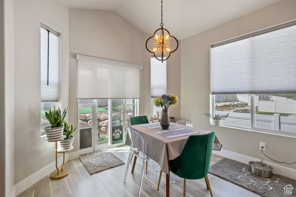 Dining room with a chandelier, wood finished floors, and vaulted ceiling