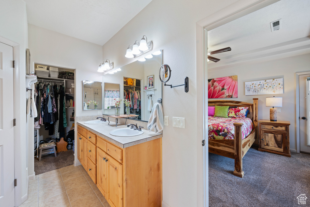 Bathroom featuring double vanity, a spacious closet, a ceiling fan, and tile patterned floors