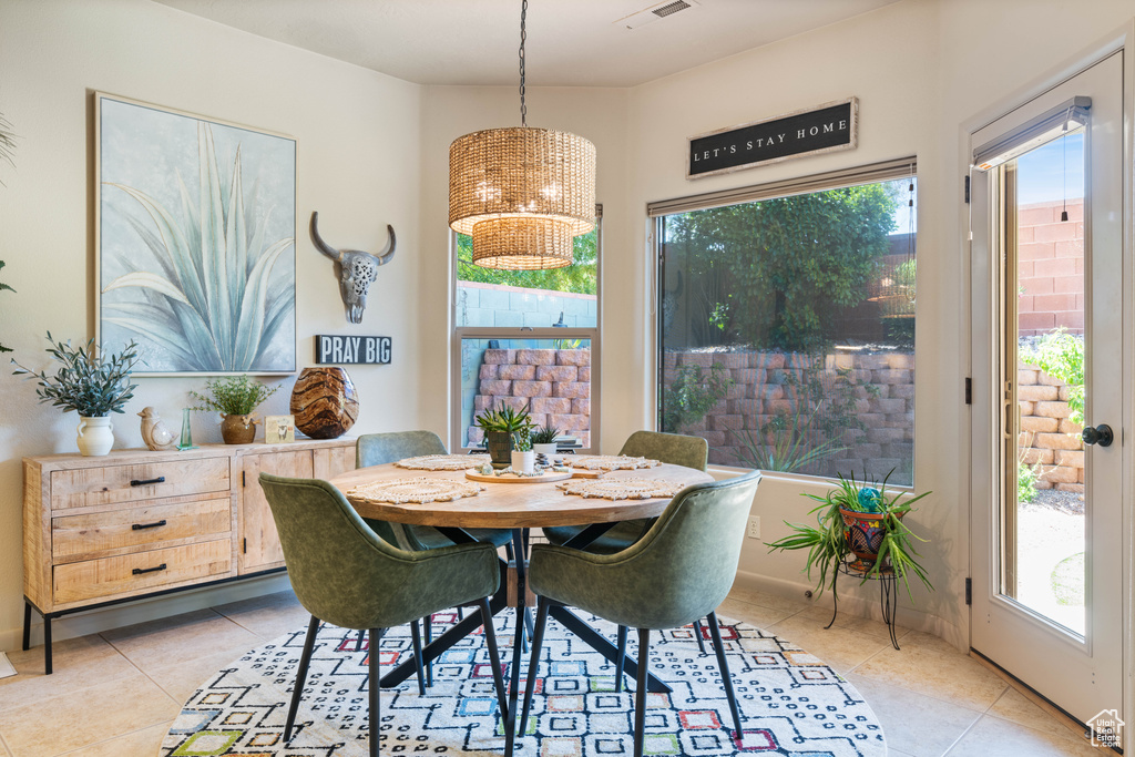 Dining area with light tile patterned flooring, healthy amount of natural light, and a chandelier