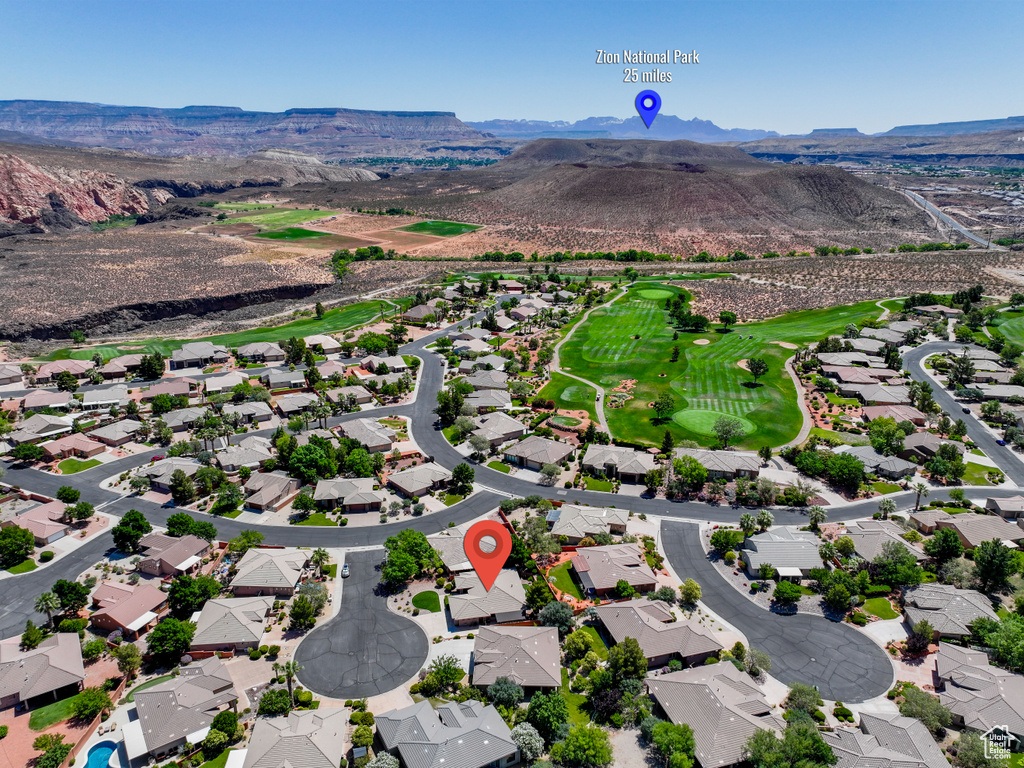 Aerial perspective of suburban area featuring a mountainous background and a golf course