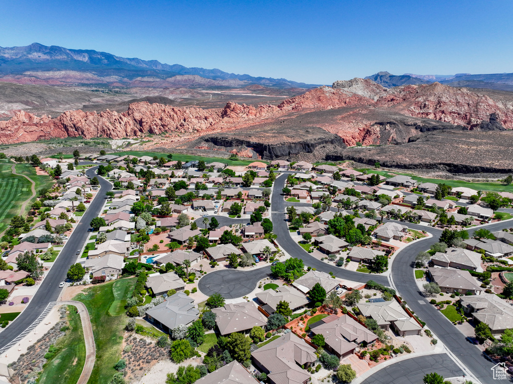 Aerial view of property and surrounding area featuring mountains and nearby suburban area