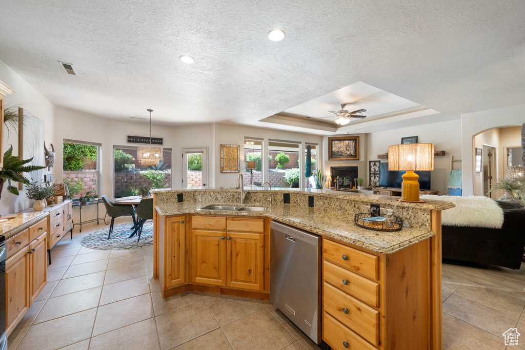 Kitchen featuring dishwasher, open floor plan, plenty of natural light, ceiling fan, and a textured ceiling