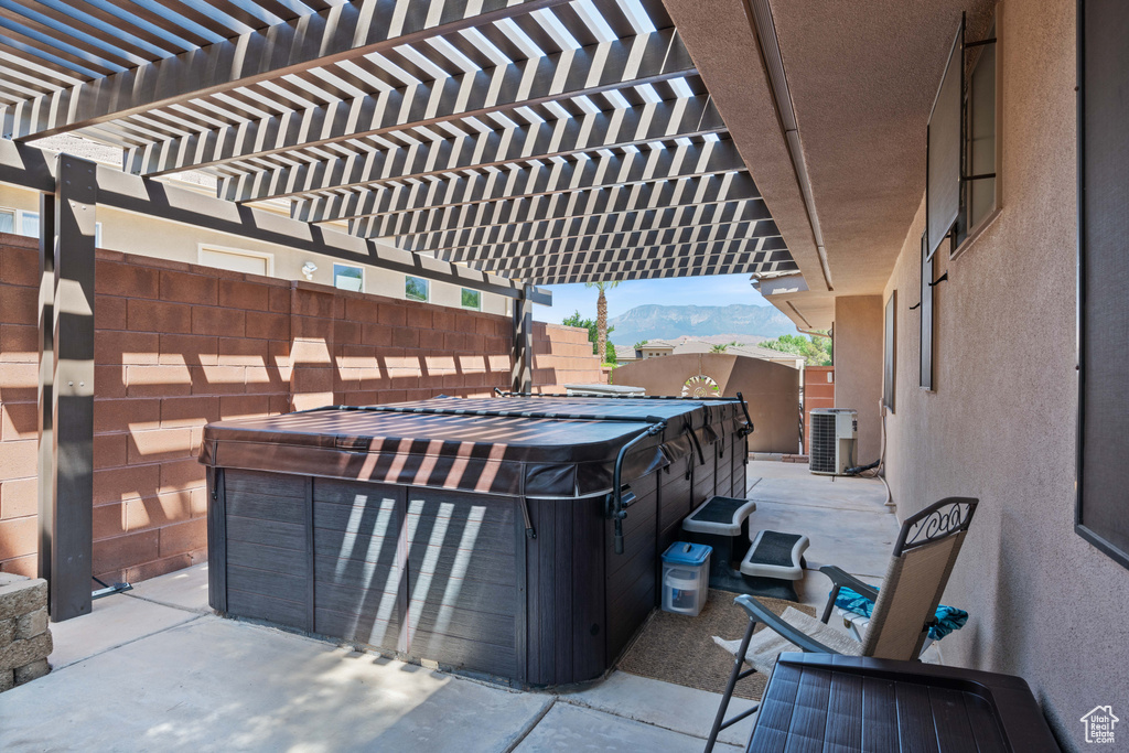 Fenced backyard featuring a hot tub, a mountain view, a patio area, and a pergola