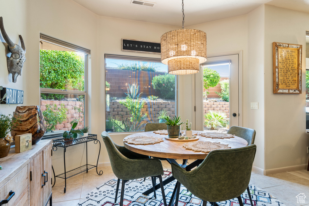Dining room featuring healthy amount of natural light, light tile patterned flooring, and a chandelier