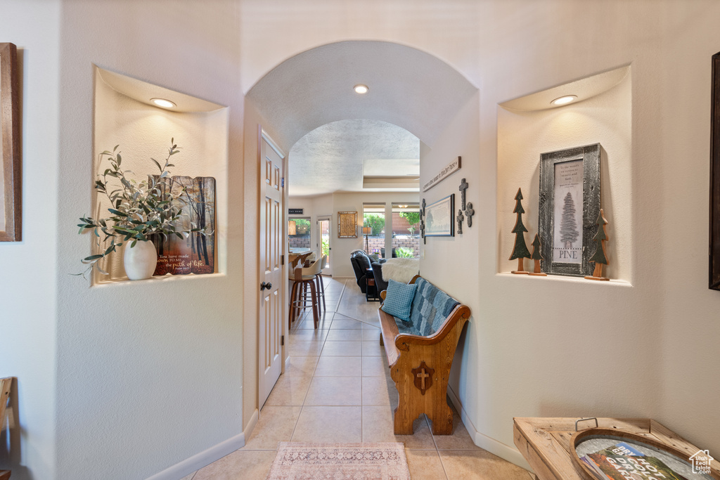 Corridor with arched walkways and light tile patterned flooring