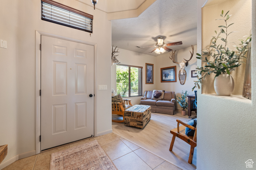 Foyer entrance with light tile patterned floors and ceiling fan