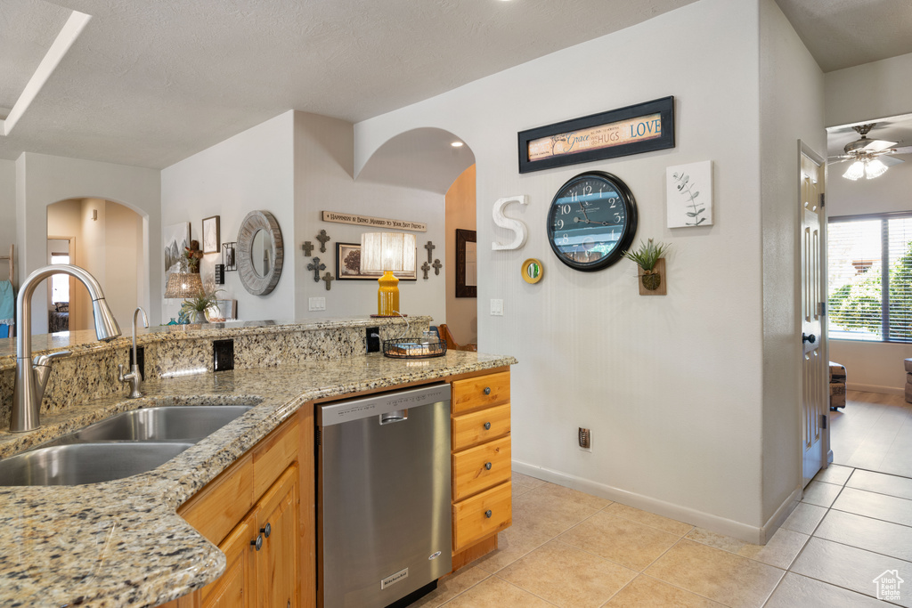 Kitchen with stainless steel dishwasher, arched walkways, ceiling fan, and light tile patterned floors