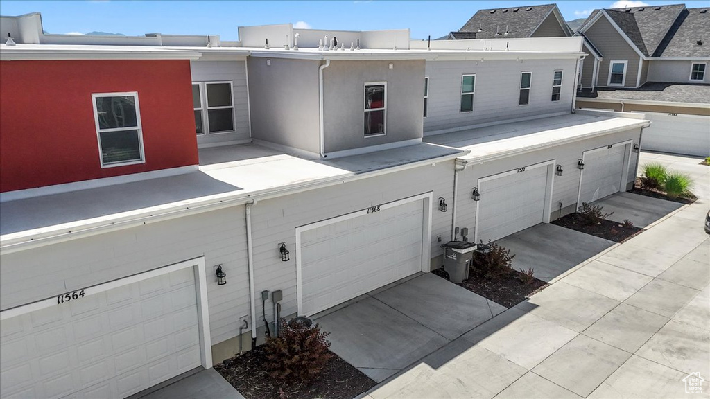 Rear view of house with an attached garage, stucco siding, and driveway