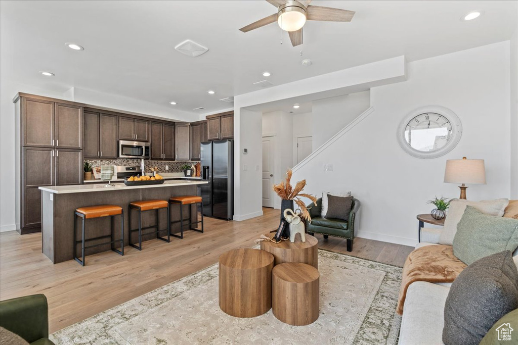 Living room with recessed lighting, ceiling fan, light wood-style flooring, and stairs