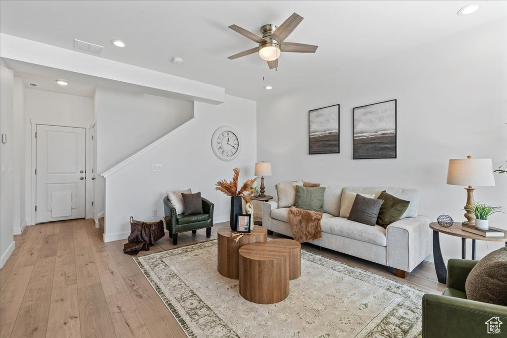 Living area featuring light wood-style floors, recessed lighting, ceiling fan, and stairway