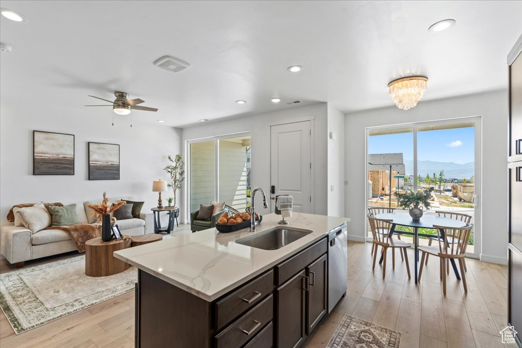 Kitchen featuring stainless steel dishwasher, light wood-type flooring, dark brown cabinetry, open floor plan, and recessed lighting