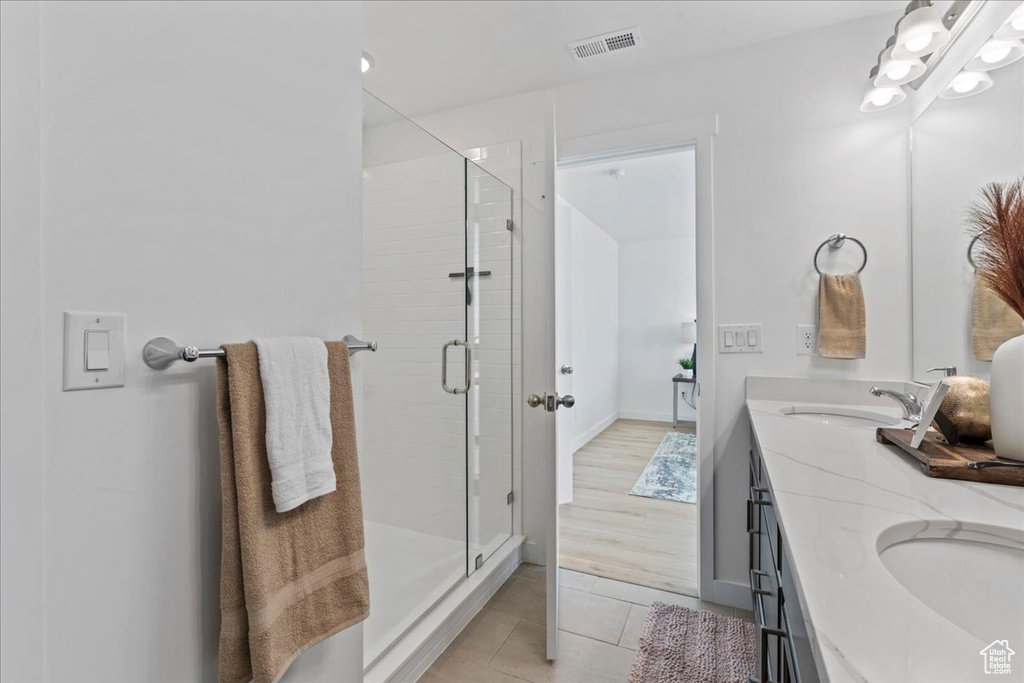 Full bathroom featuring double vanity, a stall shower, and tile patterned floors