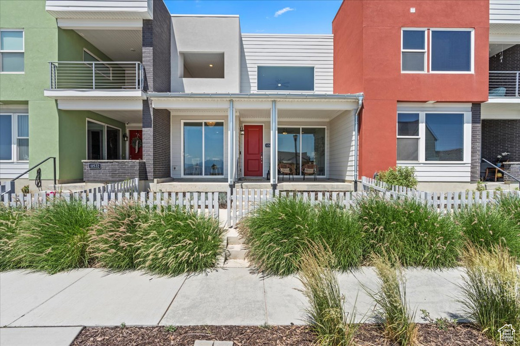 View of front of house featuring a porch, a fenced front yard, and stucco siding