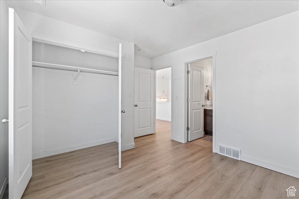 Unfurnished bedroom with a closet, light wood-style floors, and connected bathroom