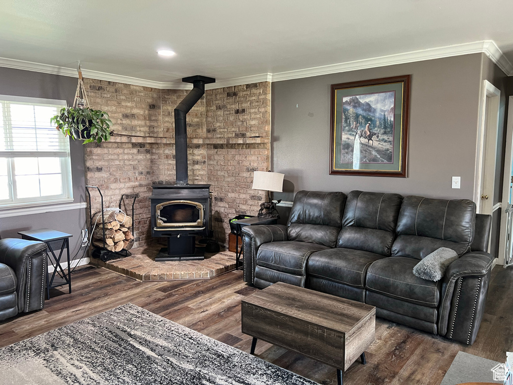 Living area featuring a wood stove, wood finished floors, and crown molding