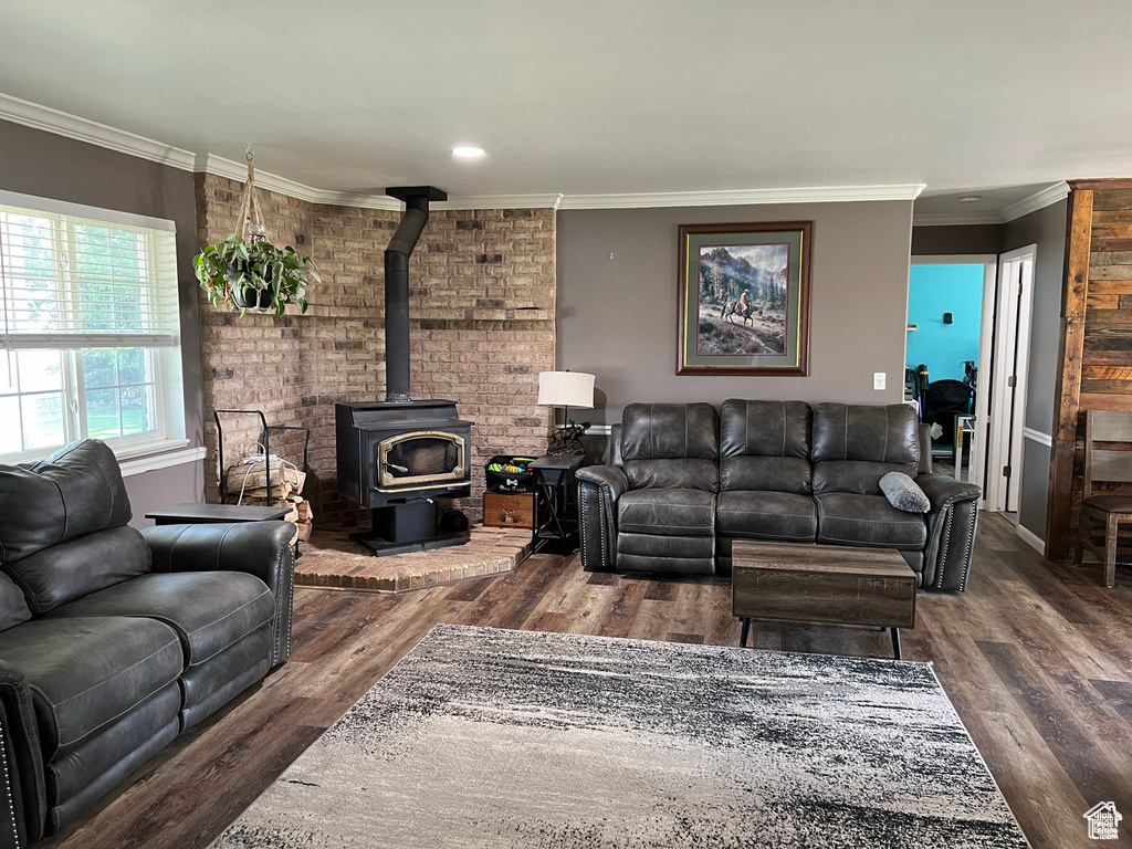Living room featuring wood finished floors, a wood stove, crown molding, and recessed lighting