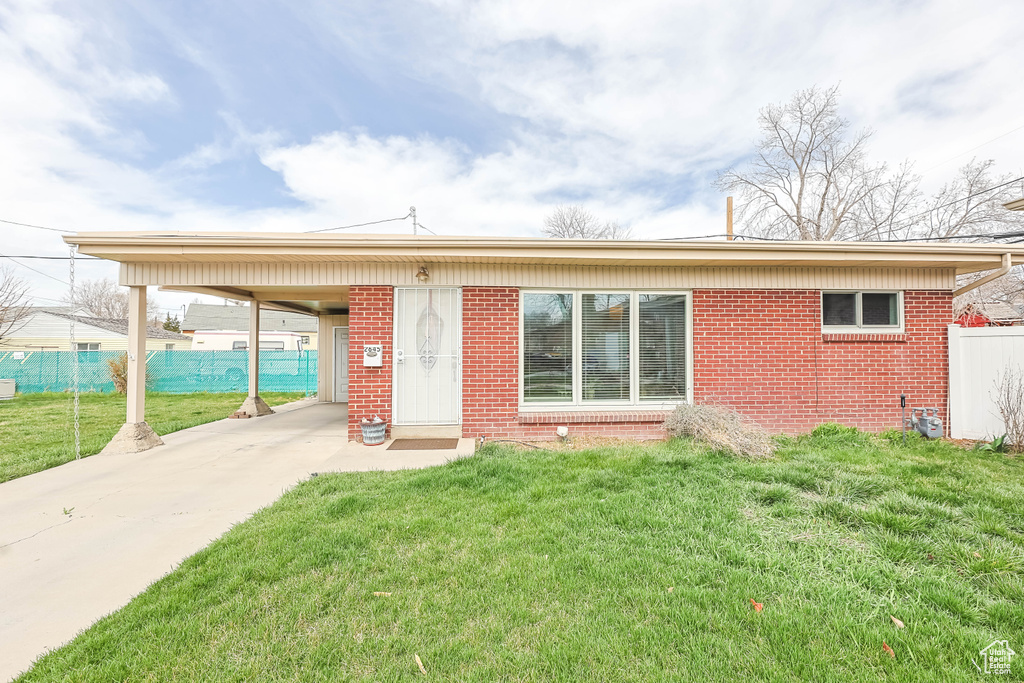 Ranch-style home featuring brick siding, a carport, and concrete driveway