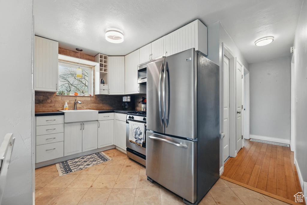 Kitchen with appliances with stainless steel finishes, dark countertops, white cabinets, decorative backsplash, and open shelves