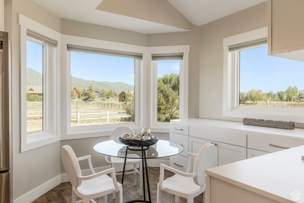 Dining room featuring dark wood-type flooring, plenty of natural light, a mountain view, and vaulted ceiling