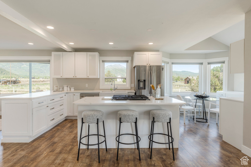 Kitchen with appliances with stainless steel finishes, a breakfast bar area, plenty of natural light, white cabinets, and recessed lighting
