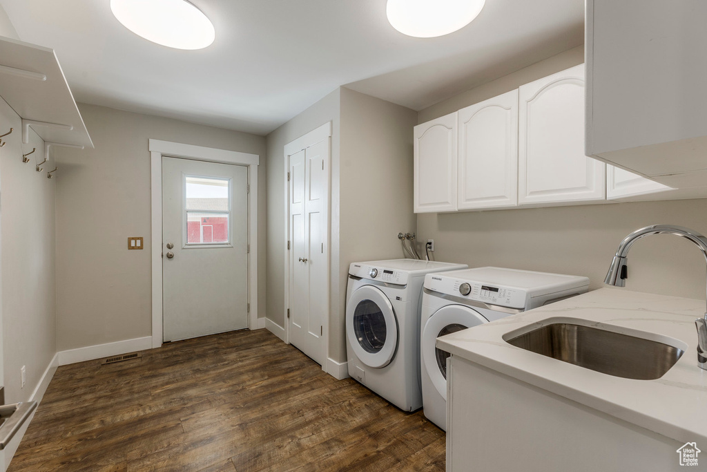 Laundry room with washing machine and dryer, cabinet space, and dark wood-style floors