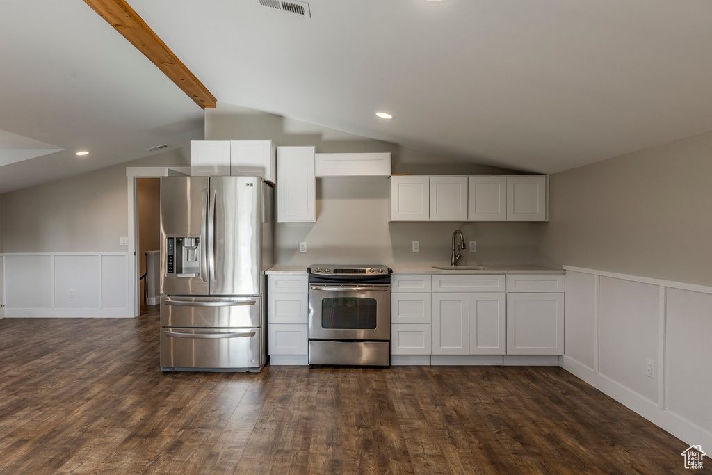Kitchen featuring appliances with stainless steel finishes, a decorative wall, dark wood-type flooring, light countertops, and white cabinets