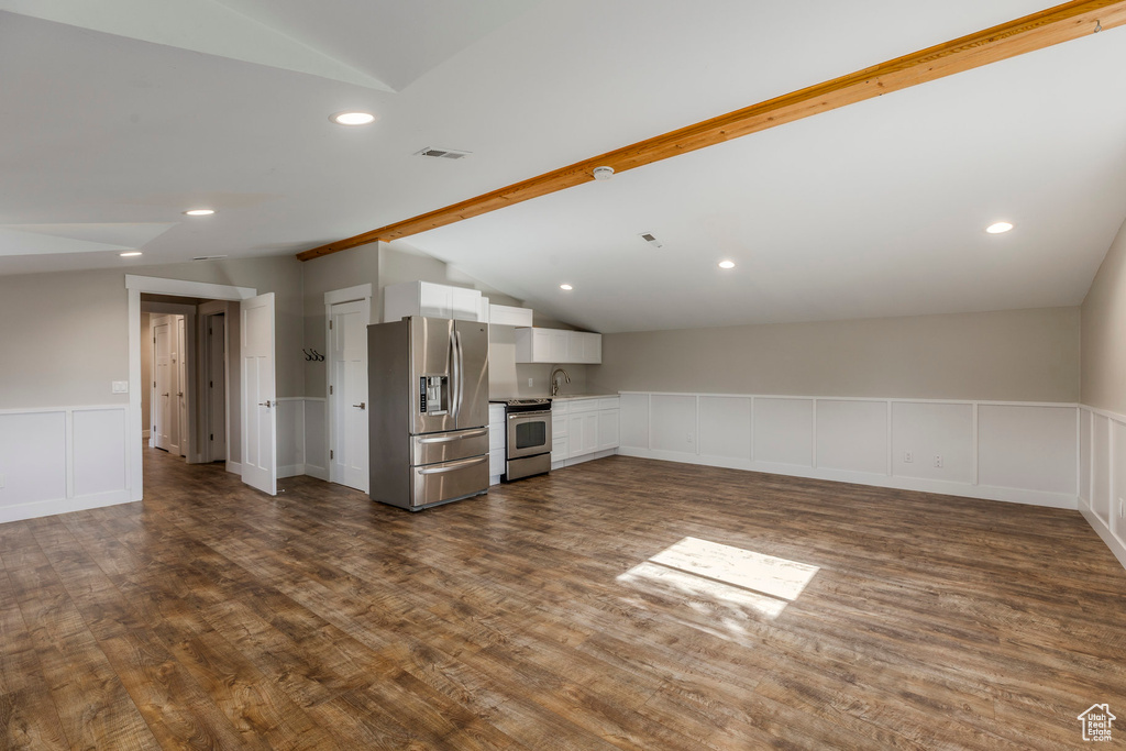Unfurnished living room with lofted ceiling, dark wood-style flooring, a wainscoted wall, a decorative wall, and recessed lighting