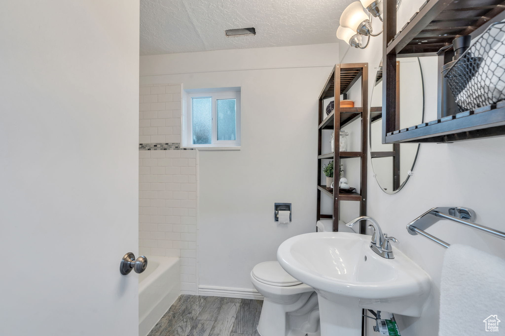 Full bath with wood finished floors, a textured ceiling, and shower / bath combination