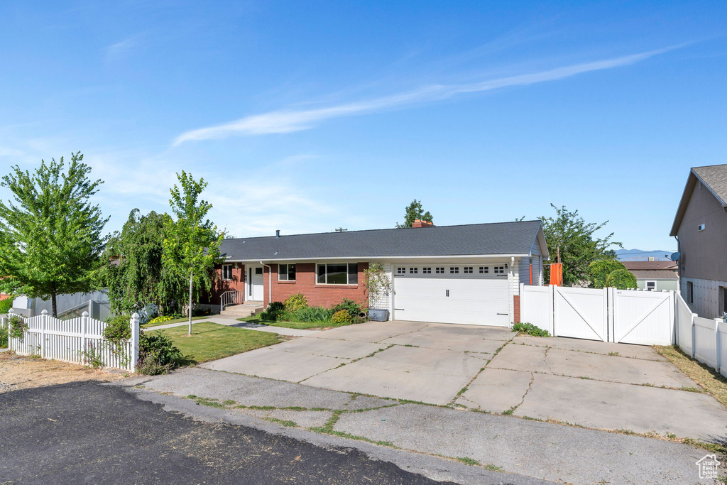 Single story home featuring a gate, a garage, driveway, and brick siding