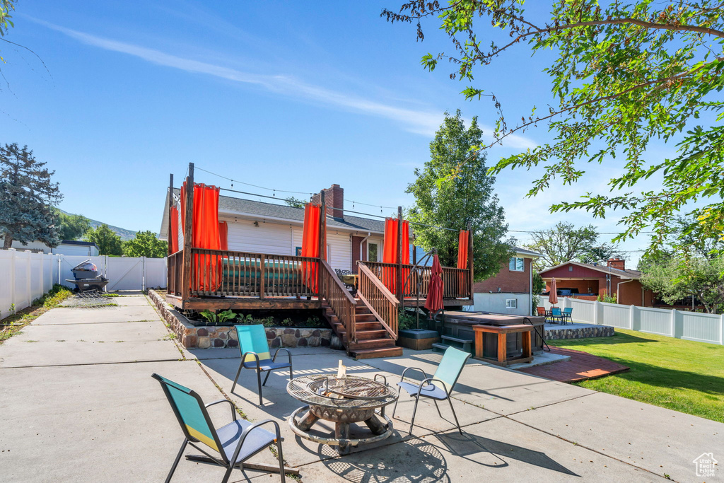 Fenced backyard featuring an outdoor fire pit, a patio area, and a wooden deck