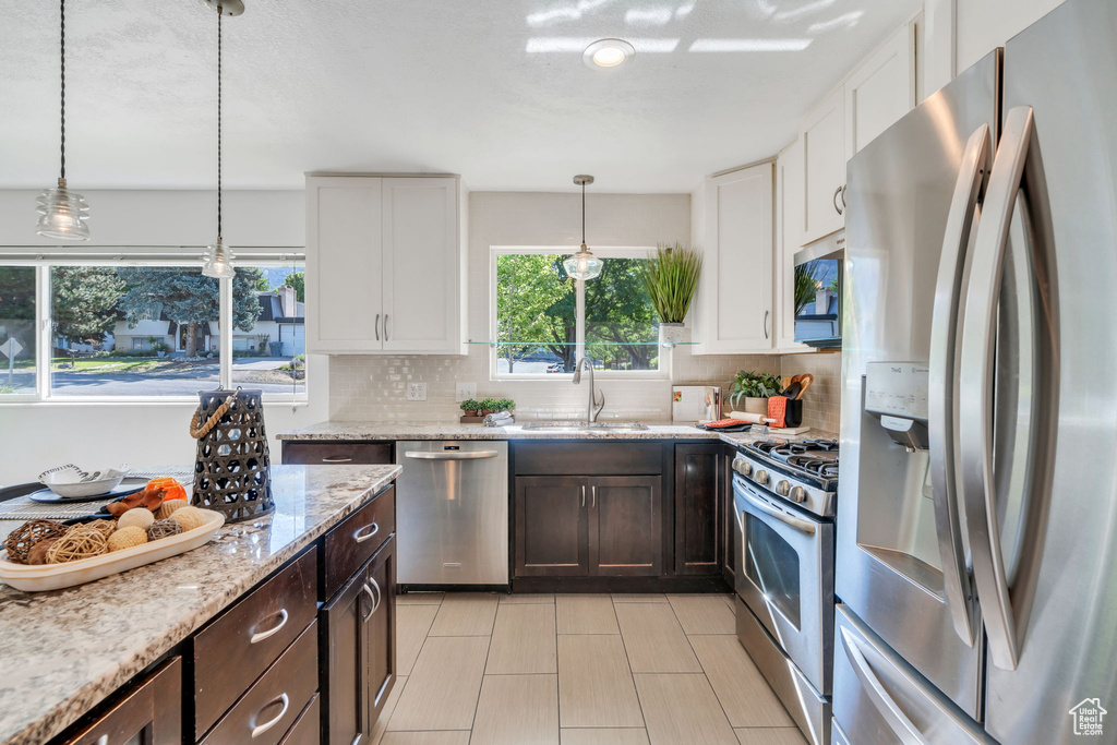 Kitchen with appliances with stainless steel finishes, dark brown cabinets, and backsplash
