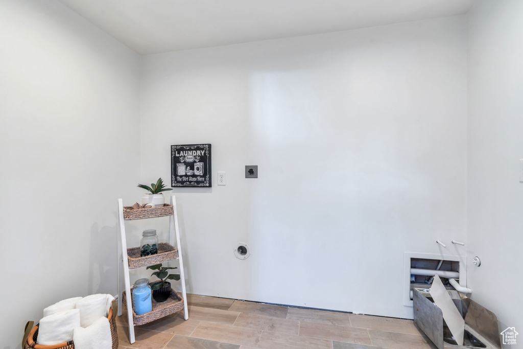 Washroom with electric dryer hookup and light wood-style flooring