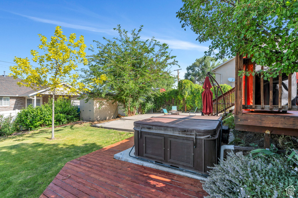 Wooden terrace featuring a hot tub and a yard