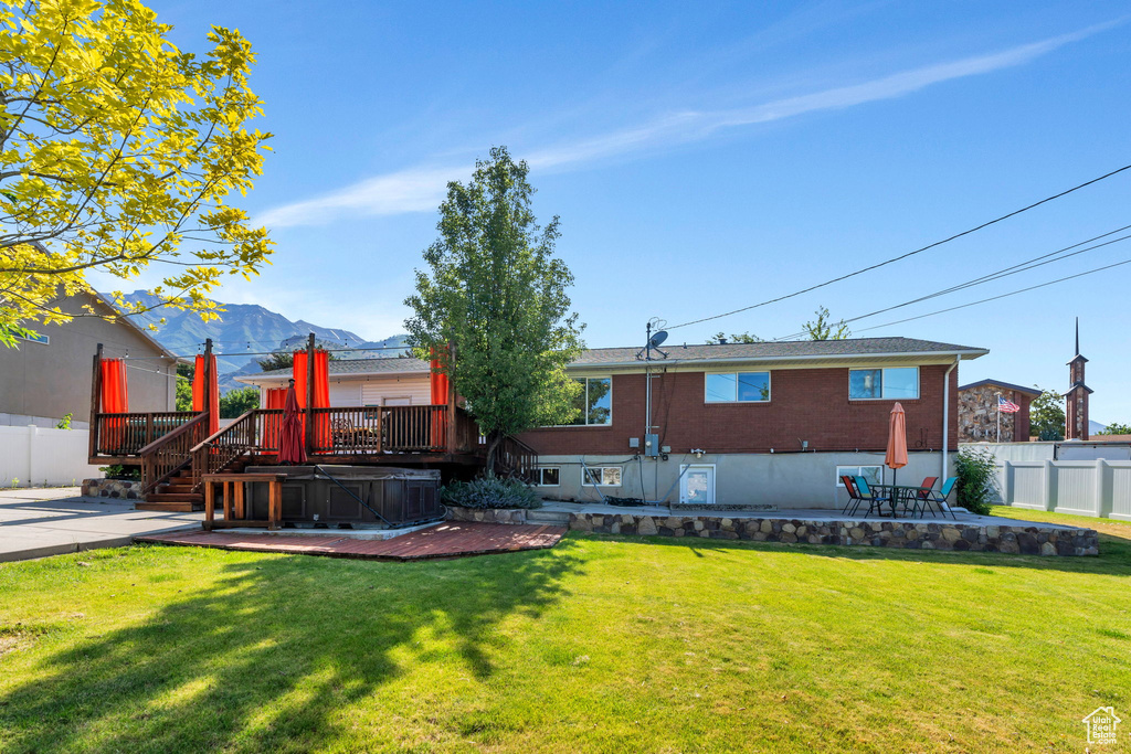 View of yard featuring a hot tub, a patio, and a deck with mountain view