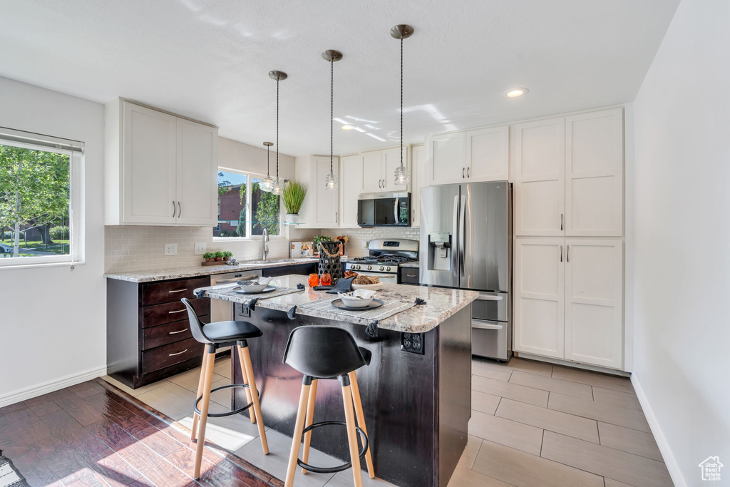 Kitchen featuring stainless steel appliances, decorative backsplash, a center island, white cabinets, and recessed lighting