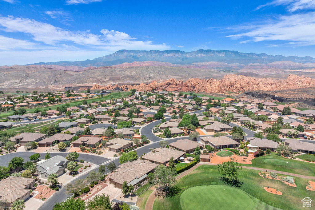 Aerial perspective of suburban area featuring a mountain backdrop and a local golf course