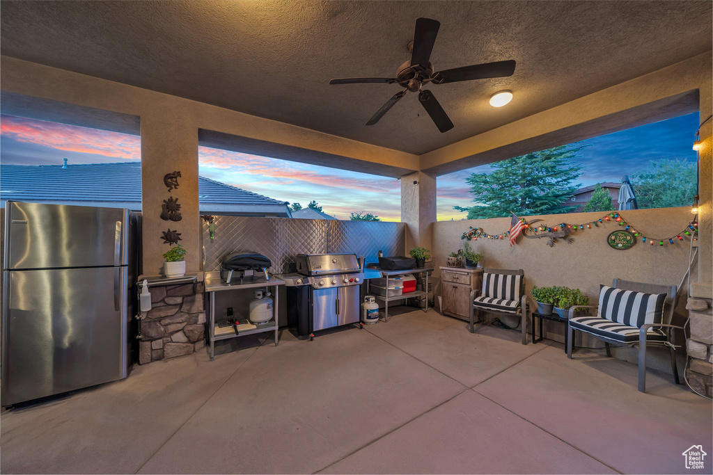 Patio terrace at dusk featuring grilling area, a patio area, and ceiling fan