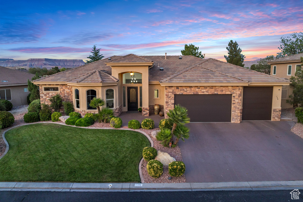 View of front of property with stone siding, an attached garage, stucco siding, and driveway