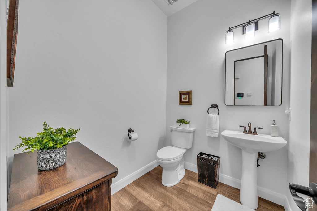 Half bath featuring wood finished floors and toilet