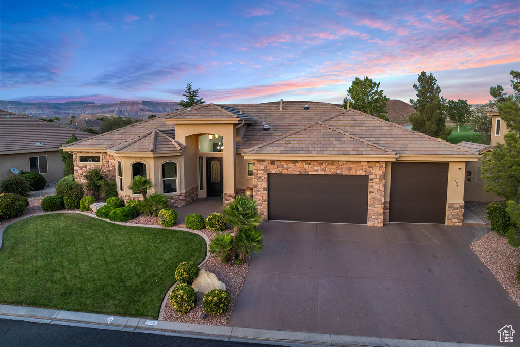 View of front of house featuring stone siding, an attached garage, stucco siding, and driveway