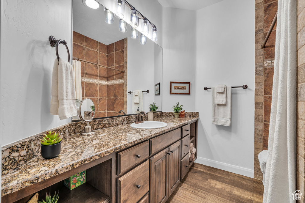 Full bathroom featuring wood finished floors, a tile shower, and vanity